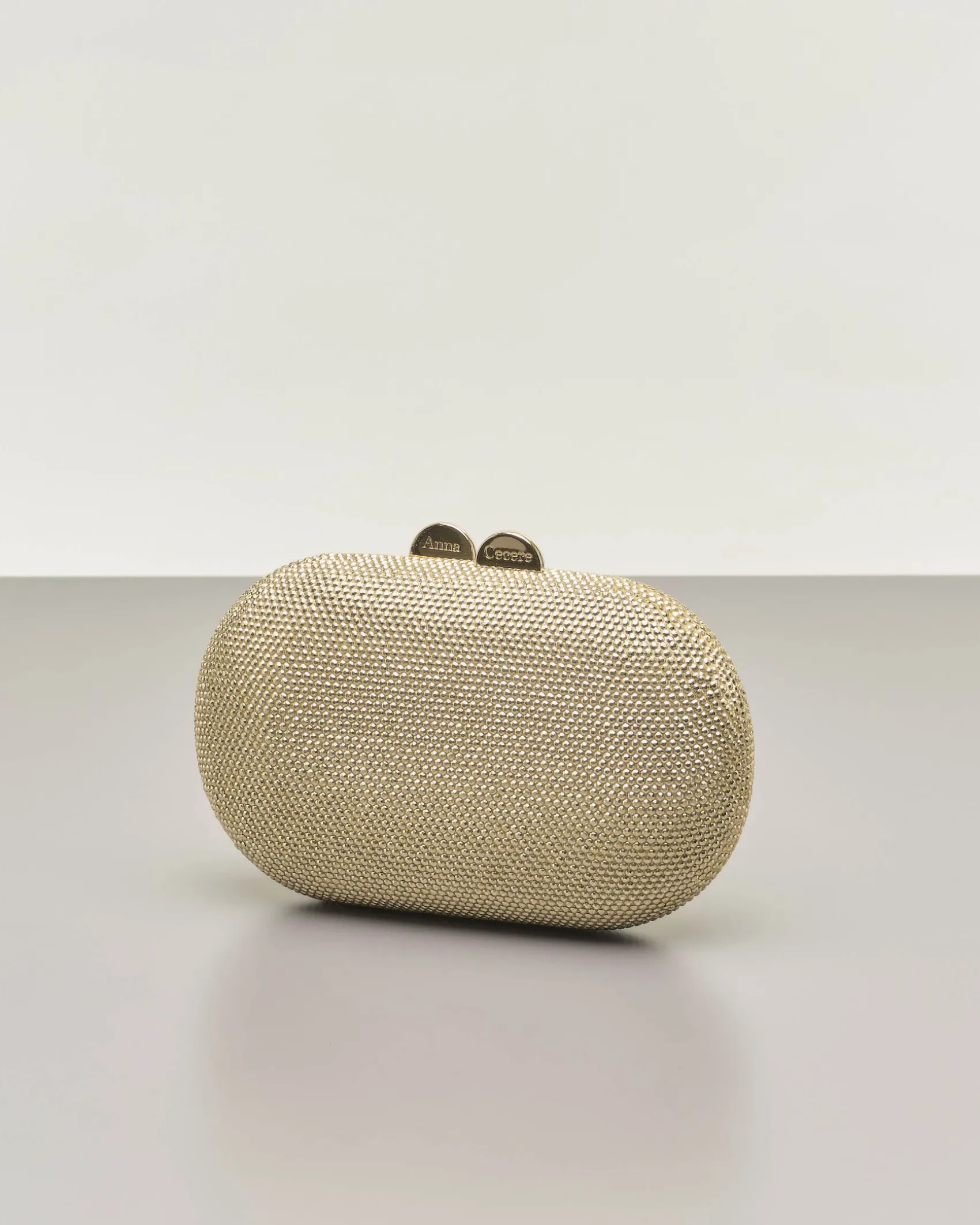 Clutch ovale color oro con strass applicati all over e chiusura a scatto a sfera