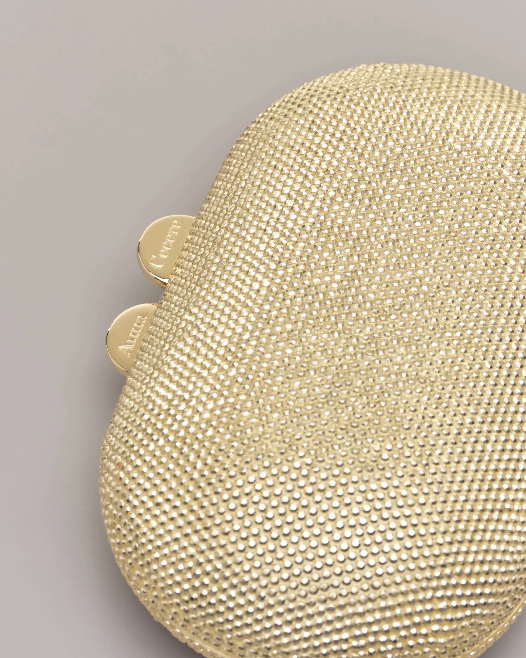 Clutch ovale color oro con strass applicati all over e chiusura a scatto a sfera