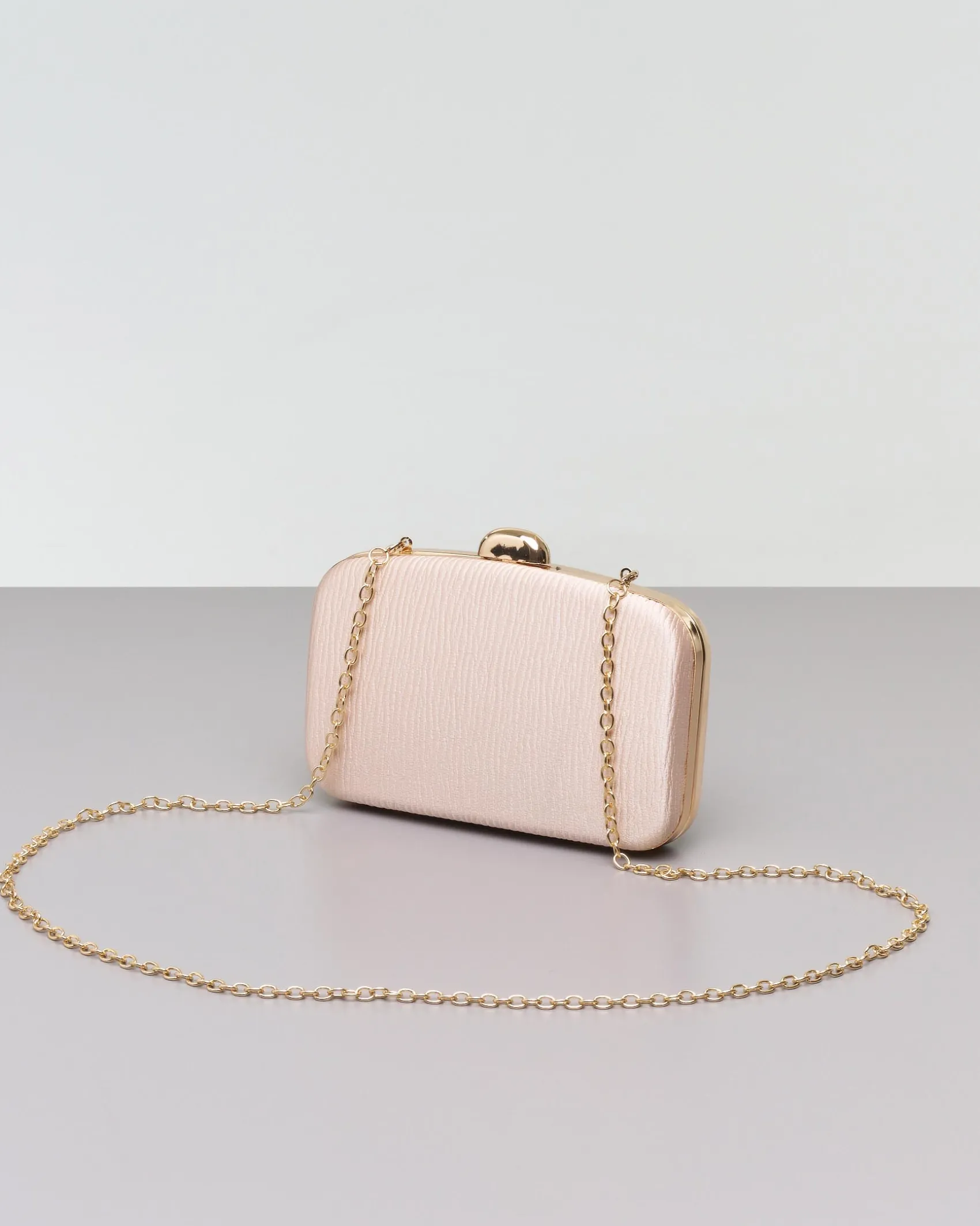 Clutch rigida color champagne in tessuto goffrato con profili e chiusura scatto in metallo dorato