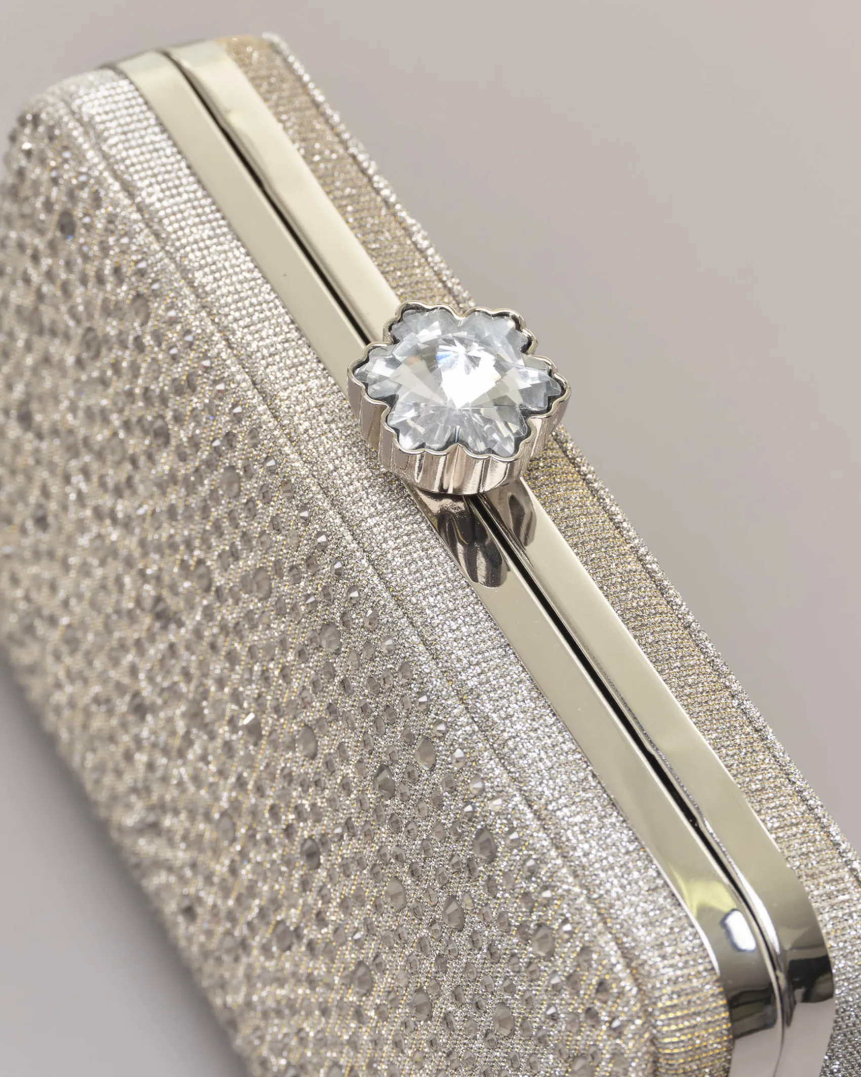 Clutch rigida color grigia in lurex con strass tono su tono applicati sul davanti e chiusura a gioiello a scatto